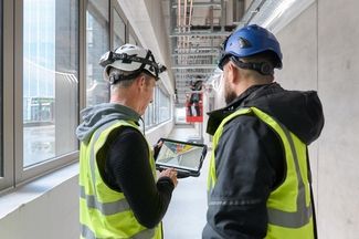 Zwei Mitarbeitende prüfen die Verlegung von Leitungen und Gebäudetechnik im Gebäude
